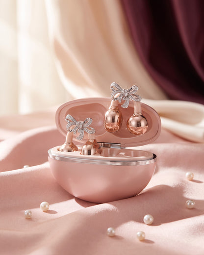 Nacary clip-on earbuds in Rosé with crystal bow charms in the open charging case