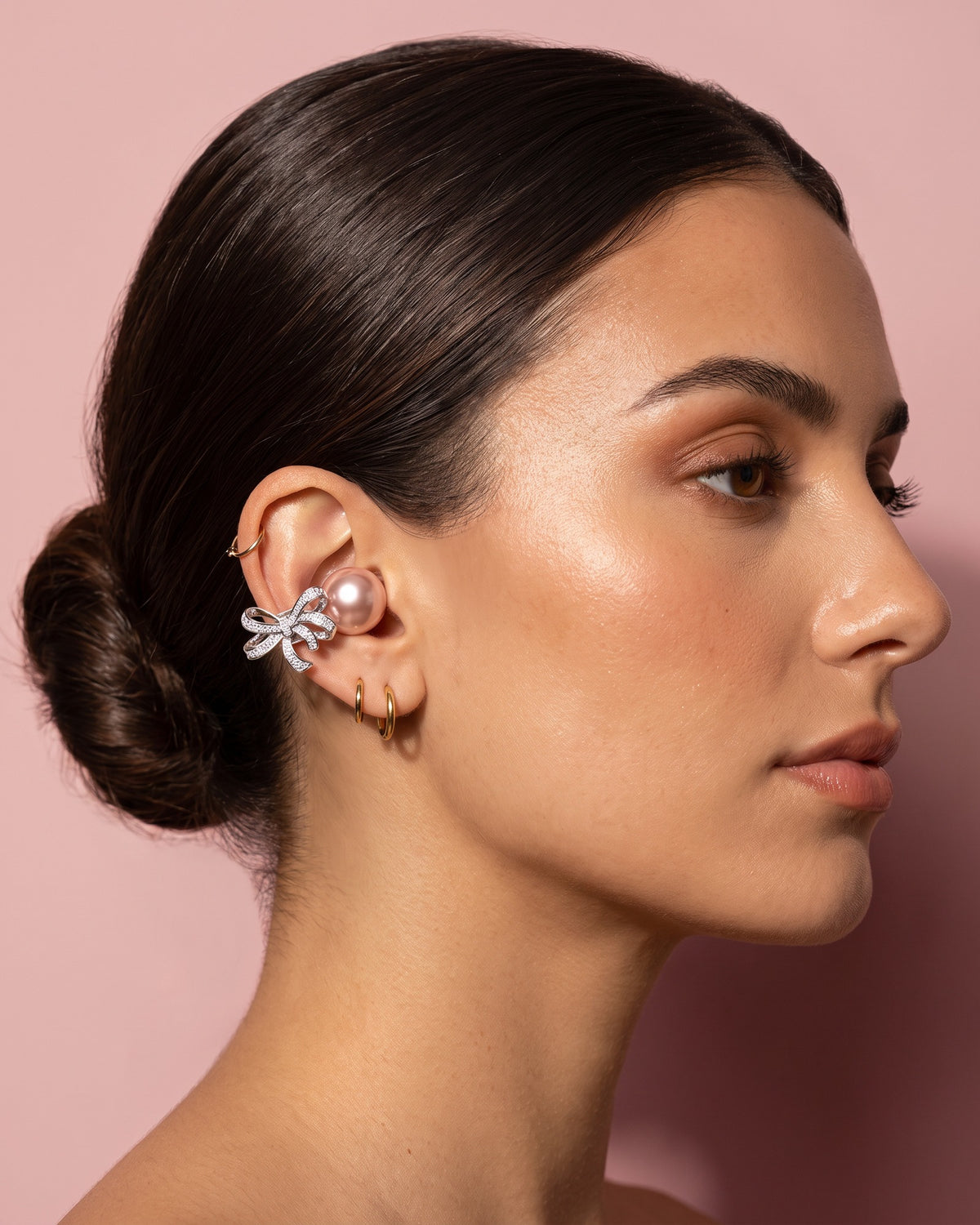 Nacary earbud worn on the outer ear next to gold hoop piercings